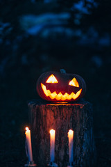 Spooky smiling halloween pumpkin in burning fire candles flames
