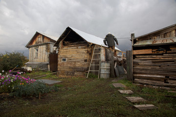 Old house of poor people out of wood. Man climbs on the roof of the old wooden house.