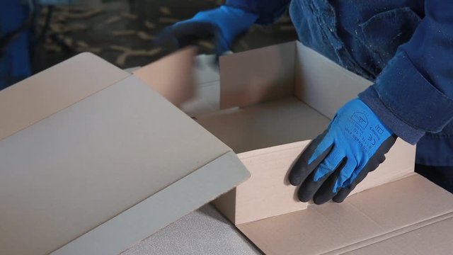 Manual assembly of carton at the factory. Manufacture of cardboard boxes.