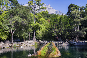 Fototapeta na wymiar Lake in the park, decorative fountain and mountain.