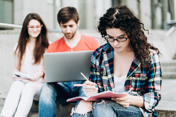 Young smart people are using gadgets and smiling while studying