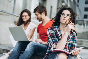 Young smart people are using gadgets and smiling while studying