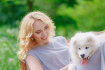 blonde girl is lying outdoors with a white dog in hands