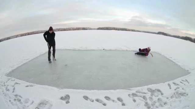Timelapse video of father and child playing hockey on the frozen ice of forest lake
