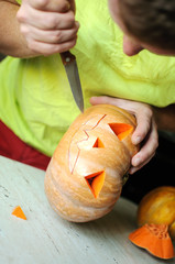 Halloween pumpkin cutting process, process of making Jack-o-lantern. Male hands with knife.