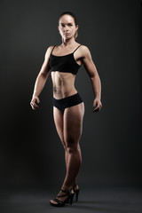 Fototapeta na wymiar athletic woman showing muscles on dark background