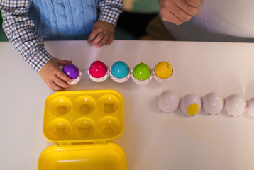 The toys on the table and father with child sitting by the table and playing by toy indoors