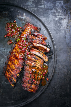 Barbecue pork spare ribs with fruit relish as top view on an old rustic board
