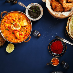 Indian cuisine on diwali holiday: tikka masala, samosa, patties and sweets with mint chutney and spices. Dark blue background. Square composition