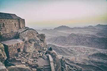 Tourists sit on a mountain and admire the dawn