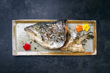 Traditional Japanese barbecue kama yaki salmon fish head as close-up on a plate