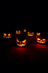 The concept of Halloween. Many glowing fiery light angry scary pumpkins. jack lantern in the dark, on a wooden background