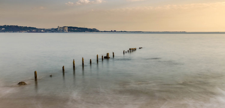 Seascape of destroyed pier on Atlantic coast in long exposure photo at sunset