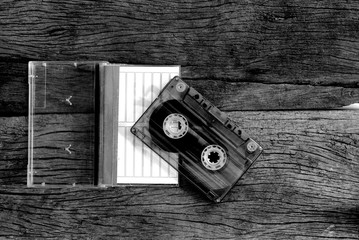 cassette tape and case on wooden floor, black and white