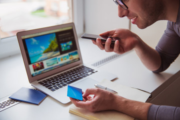 Close-up young man speaking by phone and keeping business card indoors