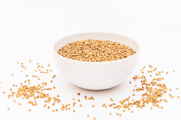 A buckwheat in round white plate on white background, a bunch of buckwheat grain in white plate, buckwheat groats