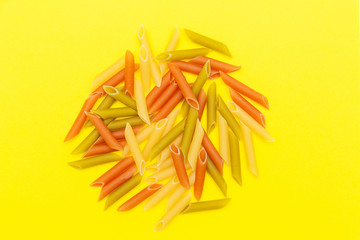 Bunch of colorful macaroni on yellow background, bunch of pasta of different colors