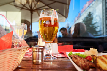 Glass of beer and street food on a cafe table.