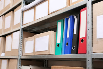 Cardboard boxes with documents on shelving unit in archive