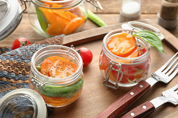 Jars with tasty carrot salad on wooden board