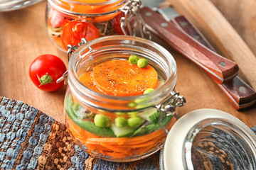 Jar with tasty carrot salad on wooden board