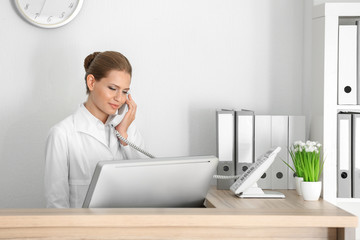 Young female receptionist talking on the phone in hospital