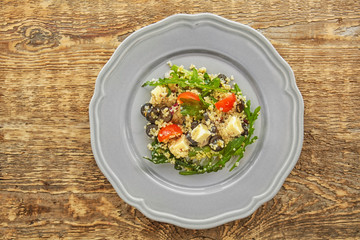 Plate with quinoa salad on wooden background