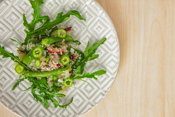 Plate with quinoa salad on table
