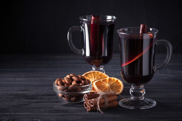 Mulled wine banner. Glasses with hot red wine and spices on dark background. Modern dark mood style.