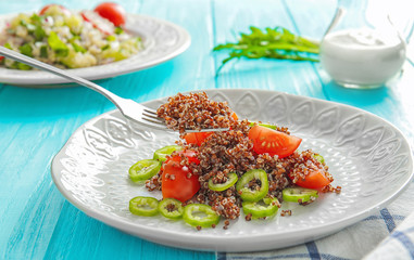 Fork and plate with delicious quinoa salad on table