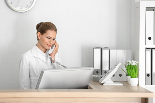 Young Female Receptionist Talking On The Phone In Hospital