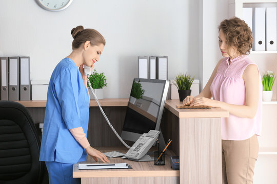 Young female receptionist with client in hospital