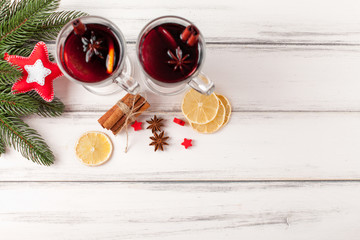 Winter horizontal mulled wine banner. Glasses with hot red wine and spices, tree, felt decorations on wooden background.