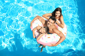 Naklejka premium Young couple and cute son with inflatable ring in pool