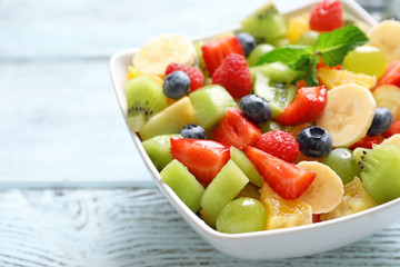 Bowl with yummy fruit salad on wooden table