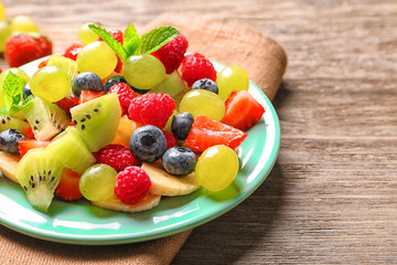 Plate with fruit salad on wooden table