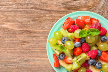 Plate with fruit salad on wooden table