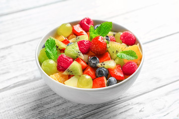 Bowl with yummy fruit salad on wooden table