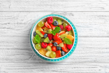 Bowl with yummy fruit salad on wooden table