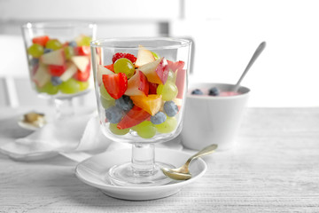 Glass with yummy fruit salad on wooden table