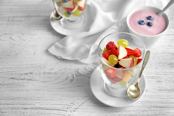 Glass with yummy fruit salad on wooden table