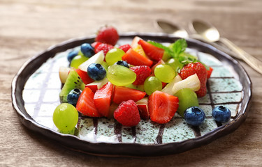 Plate with fruit salad on wooden table
