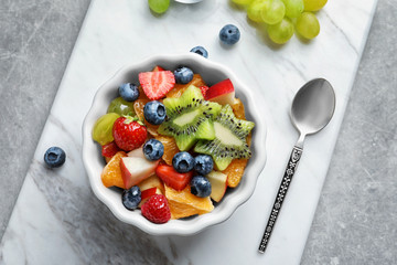 Bowl with yummy fruit salad on marble board