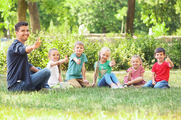 Group of children with teacher in park on sunny day