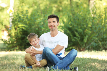 Naklejka na ściany i meble Father with son in park on sunny day