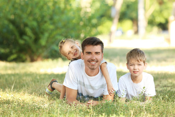 Naklejka na ściany i meble Father with children in park on sunny day