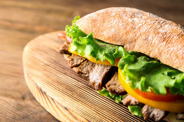 Tasty steak sandwich on wooden board
