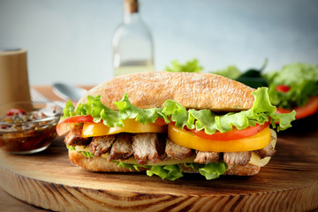 Tasty steak sandwich on wooden board