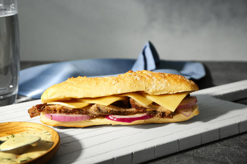 Wooden board with steak sandwich on table
