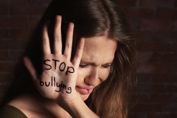 Woman with written text STOP BULLYING on palm